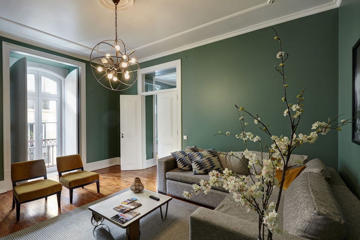 A living room with a sofa, chairs, a coffee table, and a vase with flowers.