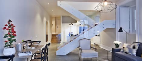 Una sala de estar moderna con una escalera, comedor y diferentes disposiciones de asientos.