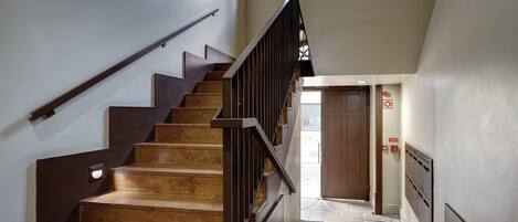 A wooden staircase with a metal handrail leading to a door at the top.