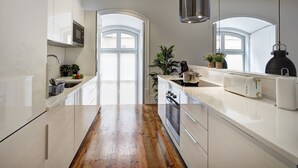 A modern kitchen with white cabinetry, a wooden countertop, and a large window with a view.