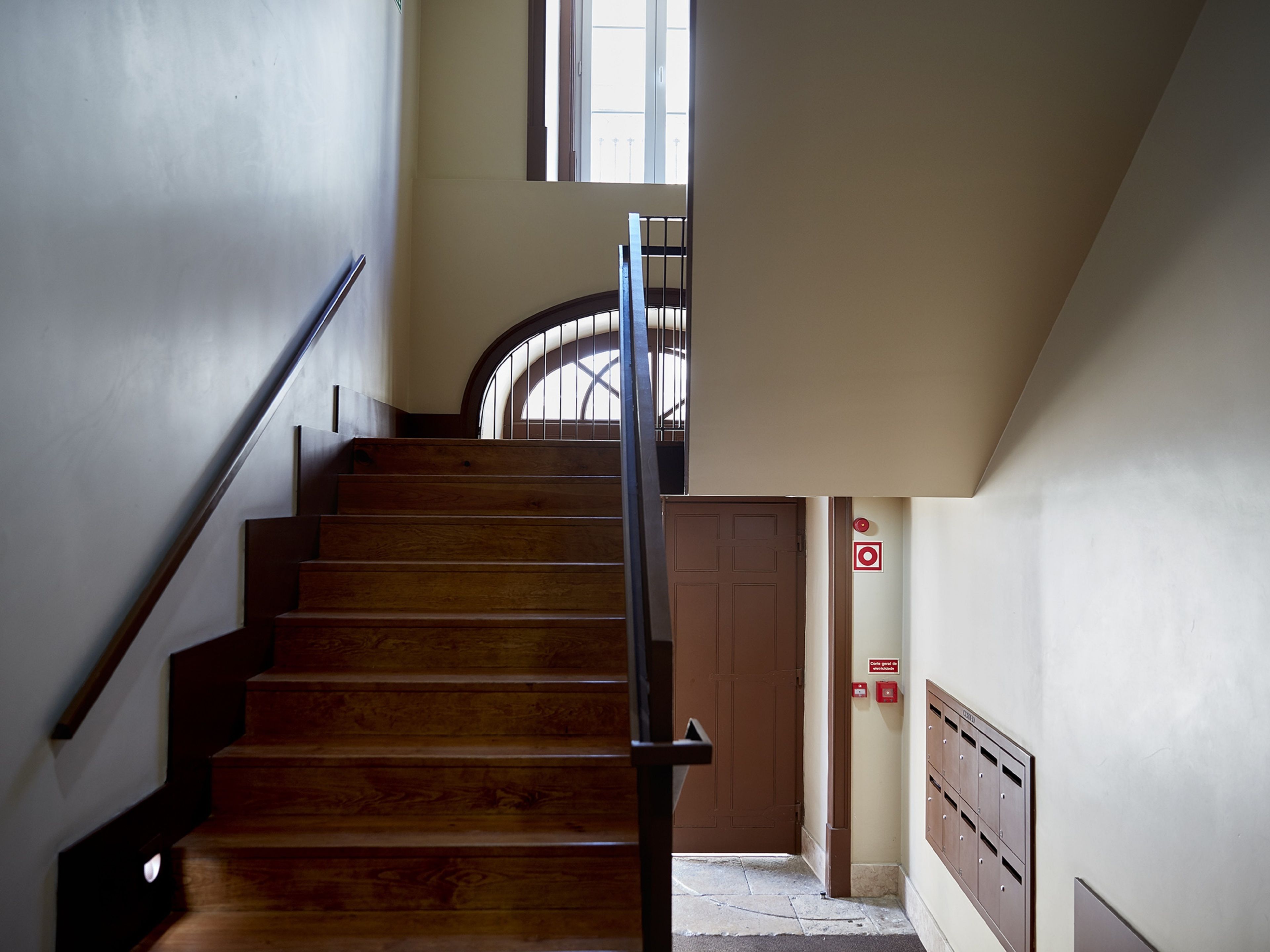 Una scala in legno con corrimano in metallo che conduce a una porta con una finestra sopra.