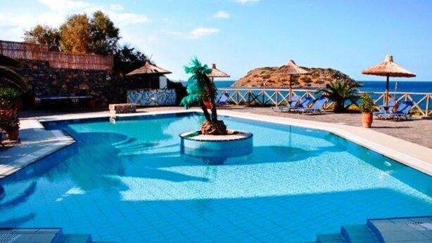 Ein Swimmingpool mit einer kreisförmigen Insel, Liegestühlen und Sonnenschirmen.