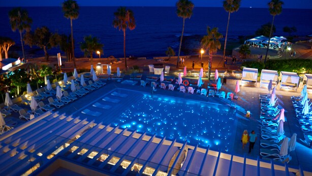 A pool area with lounge chairs and umbrellas, palm trees, and a view of the ocean. - Protur Bonamar Hotel - Adults Only (Son Servera)