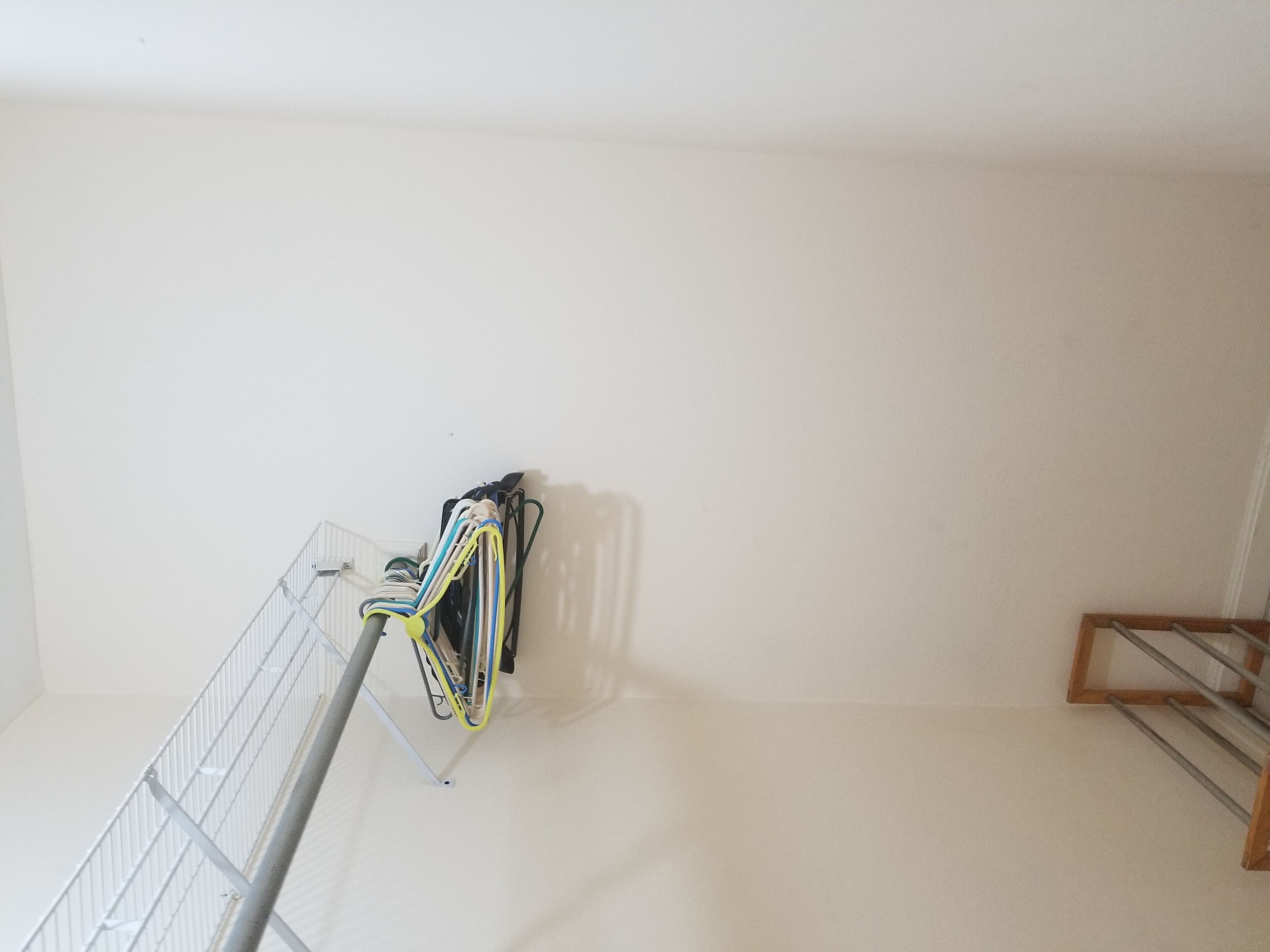 A room with a metal rack holding cables, a wooden rack, and a white wall.