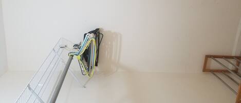 A room with a metal rack holding cables, a wooden rack, and a white wall.
