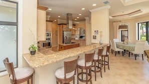 A modern kitchen with granite countertops, stainless steel appliances, and a bar area with bar stools.