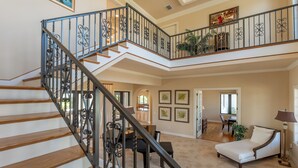 Un vaste espace de vie agrémenté d’un magnifique escalier, d’un piano et d’un coin repas.