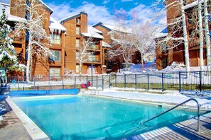 Ein Swimmingpool, umgeben von schneebedeckten Gebäuden, mit blauem Himmel.