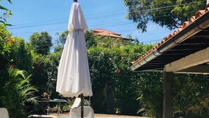 Un espace aménagé au bord de la piscine, avec une table et des chaises, un parasol blanc et une piscine.