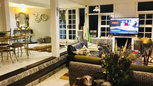 Un salon comprenant un téléviseur, un canapé et des objets de décoration. On y trouve également un coin repas avec des chaises et une table.