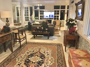 A cozy living room with a large rug, a sofa, a coffee table, and a television.