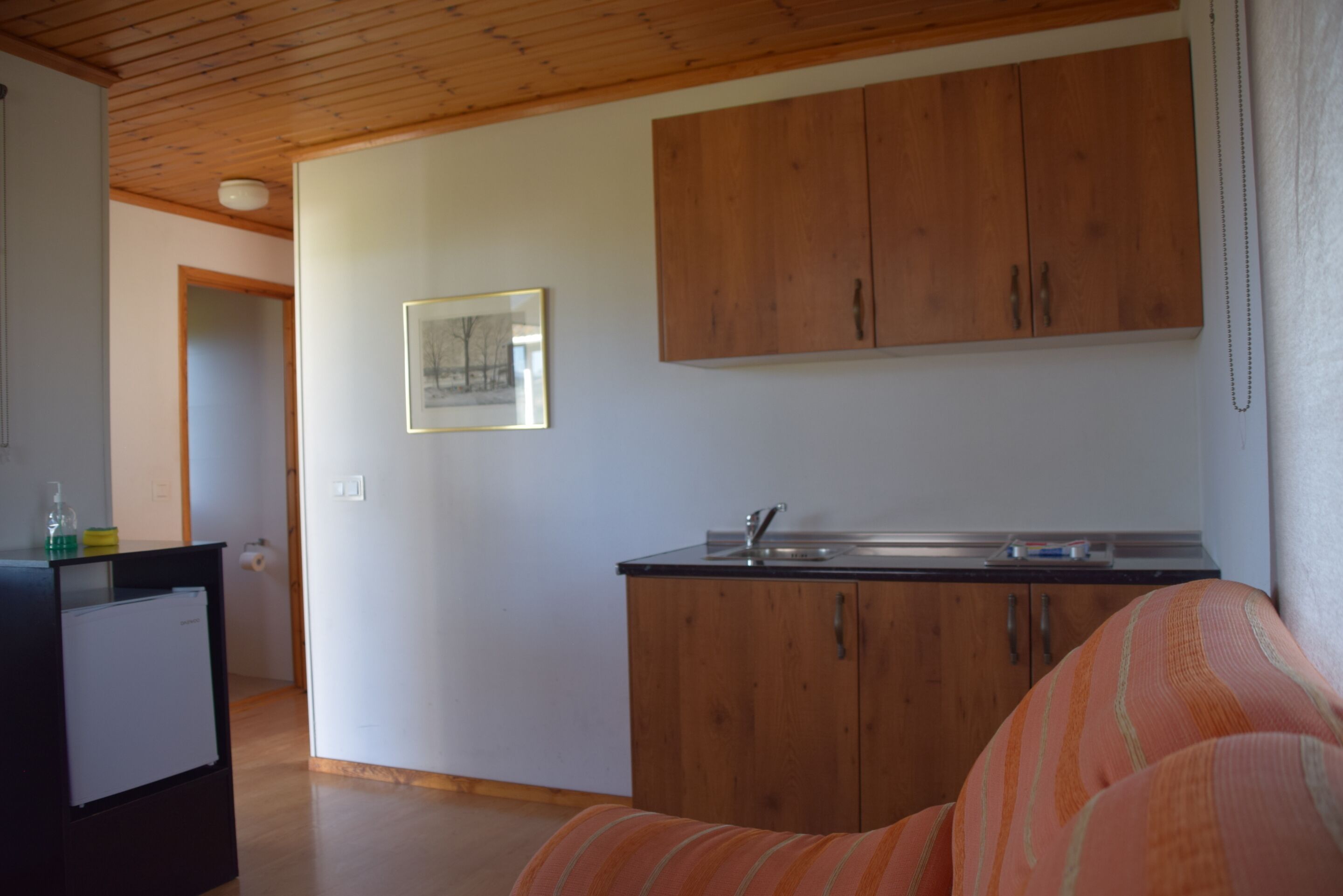 A compact kitchen with wooden cabinets, a refrigerator, and a sink.
