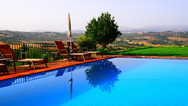 Piscina con sillones de descanso y vistas al campo.
