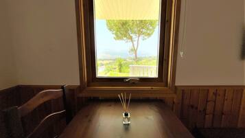 Una mesa de comedor con vista despejada a un balcón y un árbol.
