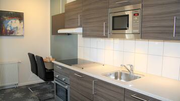A modern kitchen with a built-in microwave, stainless steel sink, and wooden cabinets.