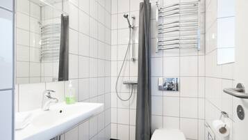 A modern bathroom with a white sink, a toilet, and a shower area.