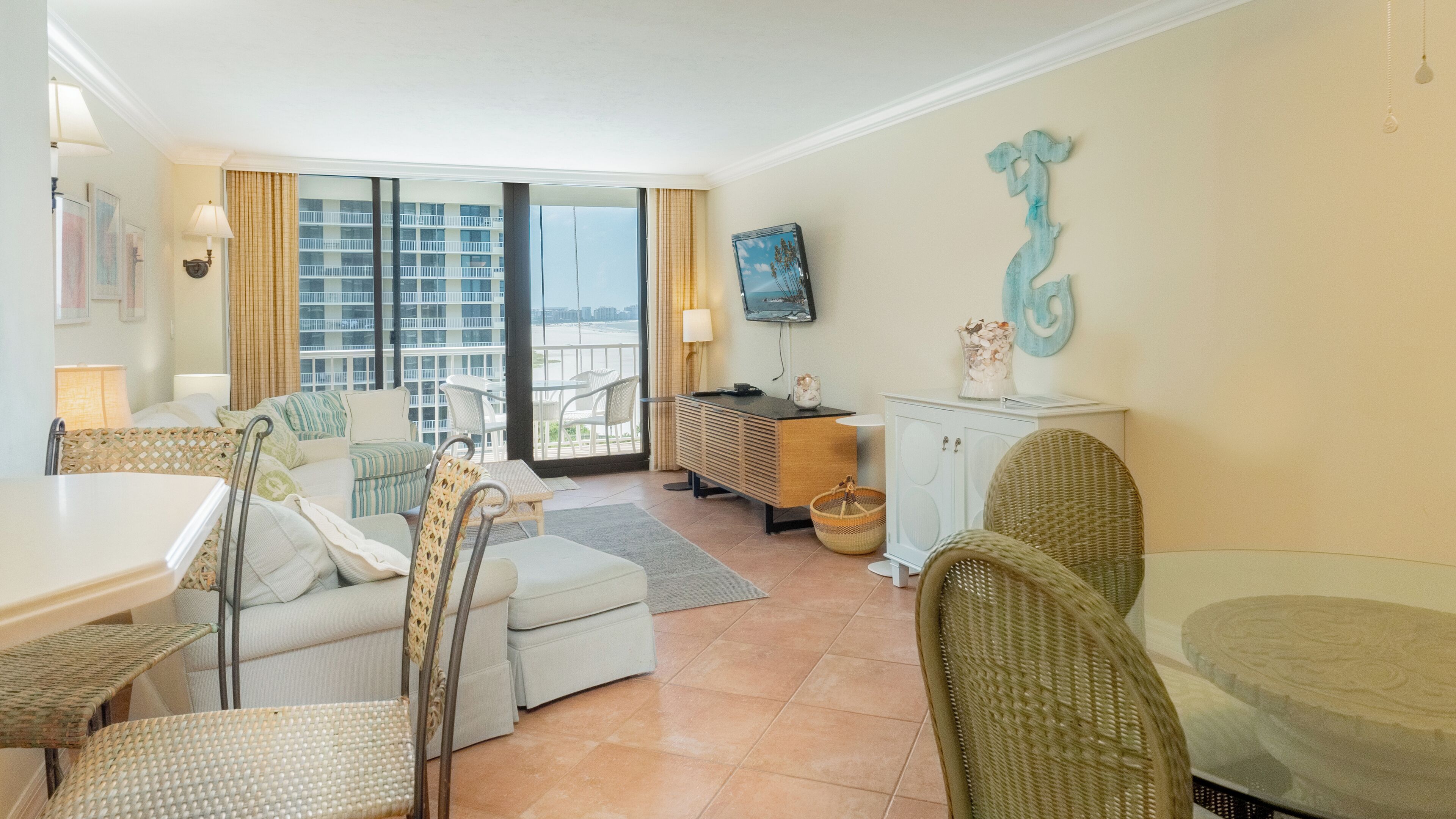 Une chambre d’hôtel avec un balcon, une télévision, un coin repas et un canapé.