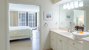 Una habitación de hotel con cama, baño con lavamanos y espejo, y vista a un edificio por la ventana.