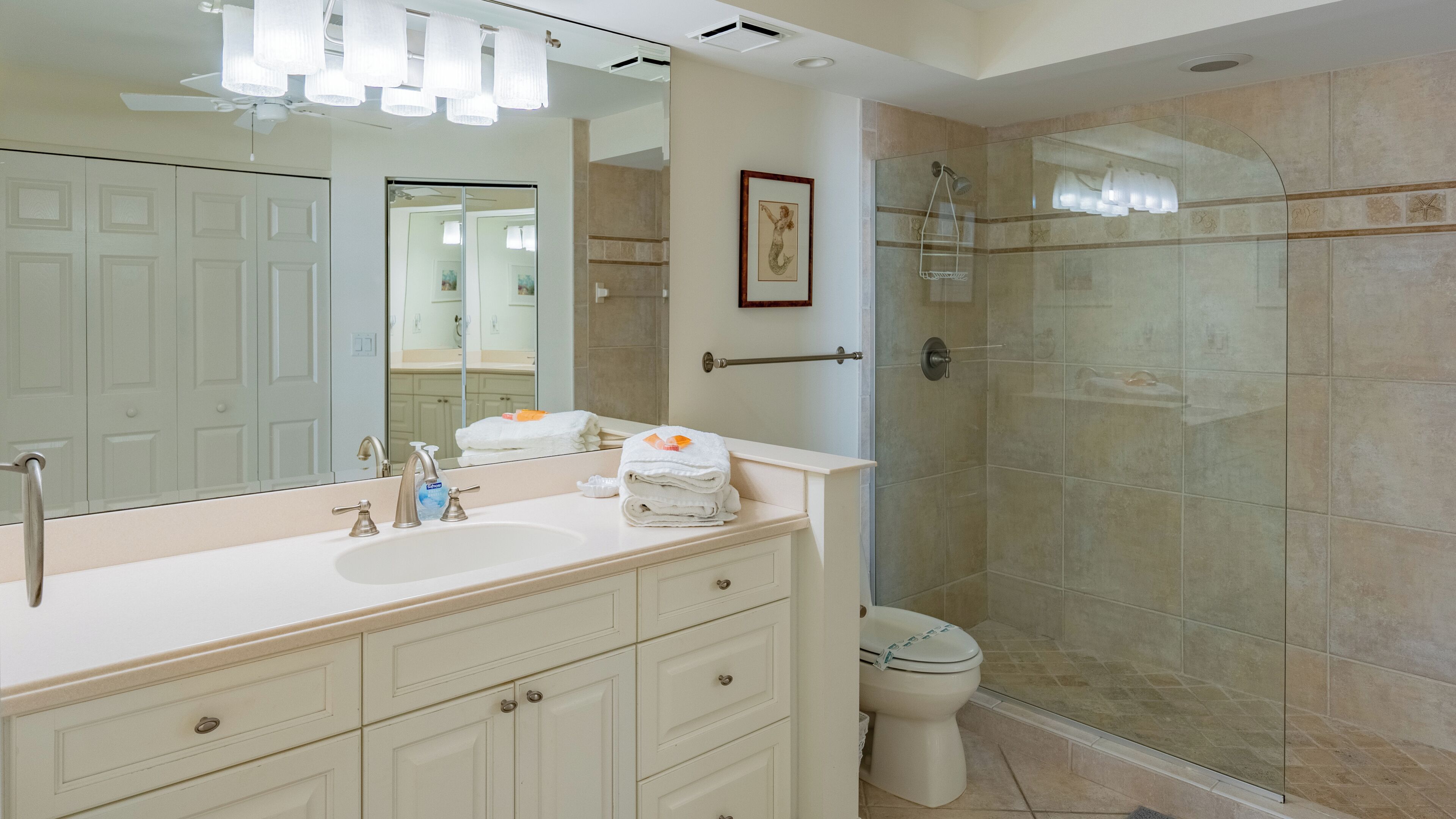 A modern bathroom with a large mirror, two sinks, a toilet, and a glass shower enclosure.