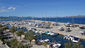 A marina with numerous boats docked, a clear sky, and a mountainous backdrop. - Harborfront Escape in Mallorca (Ca'n Picafort)