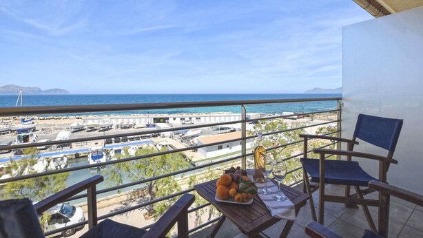 A balcony with a table set for a meal, overlooking a marina and the sea. - Harborfront Escape in Mallorca (Ca'n Picafort)