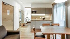 Une cuisine moderne équipée d’un four à micro-ondes, d’un évier et de meubles en bois. Un coin repas avec une table et des chaises est également disponible.