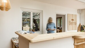 Un espace d’accueil avec un comptoir en bois, une grande fenêtre et une enseigne indiquant « Bernina ».