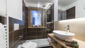 Une salle de bain moderne avec une douche à parois de verre, un lavabo blanc et un meuble-lavabo en bois.