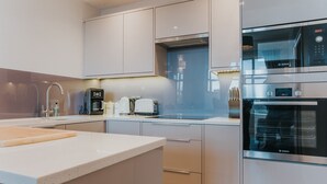 Une cuisine moderne avec des meubles blancs, un four Bosch et une machine à café.