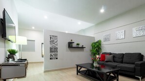 A modern living room with a black sofa, a coffee table, a flat-screen TV, a lamp, and a wall with motivational quotes. - New historic center apartment (1) 200 meters from the boardwalk  (Zona Comercial)