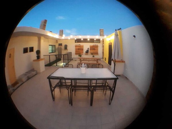 A dining area with a table and chairs, a staircase, and a view of the sky.