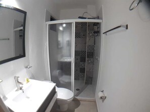 A bathroom with a white sink, toilet, and a glass-enclosed shower area.