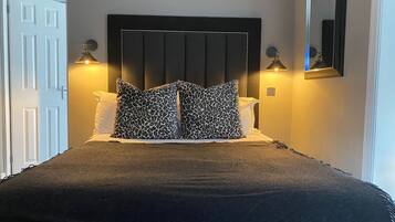 A bedroom with a dark headboard, two bedside lamps, and a bed with a dark cover.