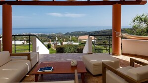 An outdoor seating area with a view of the sea and hills.