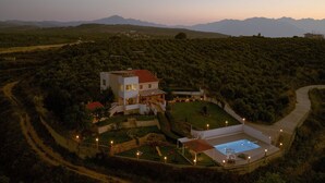 A modern two-story house with a swimming pool, surrounded by a landscaped garden and a winding road.