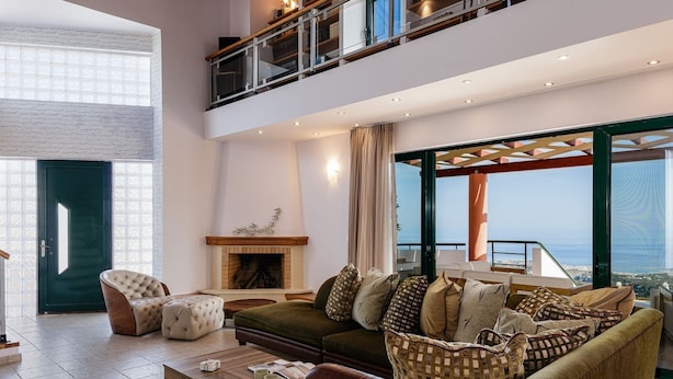 A spacious living area with a fireplace, comfortable seating, and a balcony with a view.