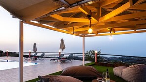 A rooftop terrace with a pool, lounge chairs, and a table with a bottle and glasses.