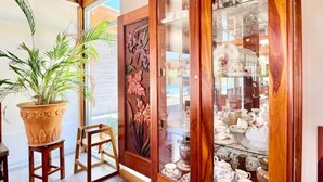 A room with a wooden cabinet displaying various dishes and a potted plant. - Richardson Serenity Villa (Roatan)