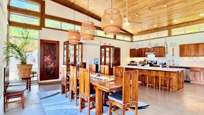 A spacious kitchen with wooden cabinets, a central island, and hanging wicker light fixtures. - Richardson Serenity Villa (Roatan)