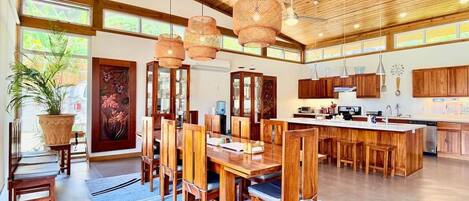 Una cocina amplia con armarios de madera, una isla central y lámparas de mimbre colgantes.