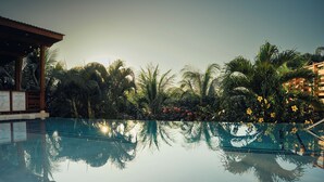 A clear pool with reflections of palm trees and a building. - Richardson Serenity Villa (Roatan)