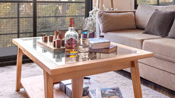Una sala de estar moderna con una mesa de centro de vidrio, un sofá y vistas de un edificio a través de grandes ventanales.