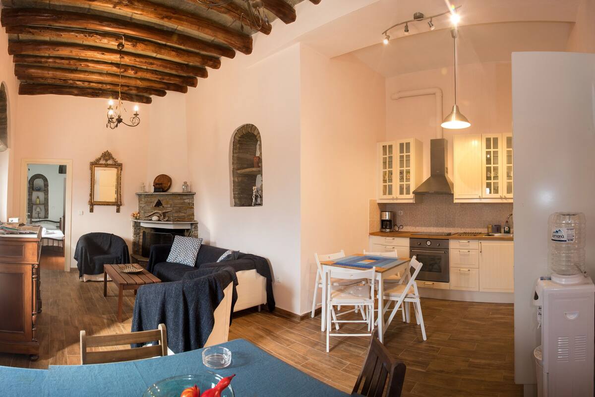 A cozy living room with a fireplace, a dining area, and a kitchen with white cabinets.