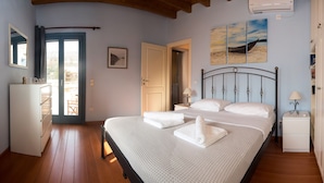 A bedroom with a bed, bedside tables, a wardrobe, a radiator, and a window. - Petra Traditional House (Andros)
