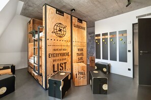 A modern hotel lobby with wooden lockers, a map on the wall, and a concrete ceiling. - Stories by Grimm‘s (Münster)