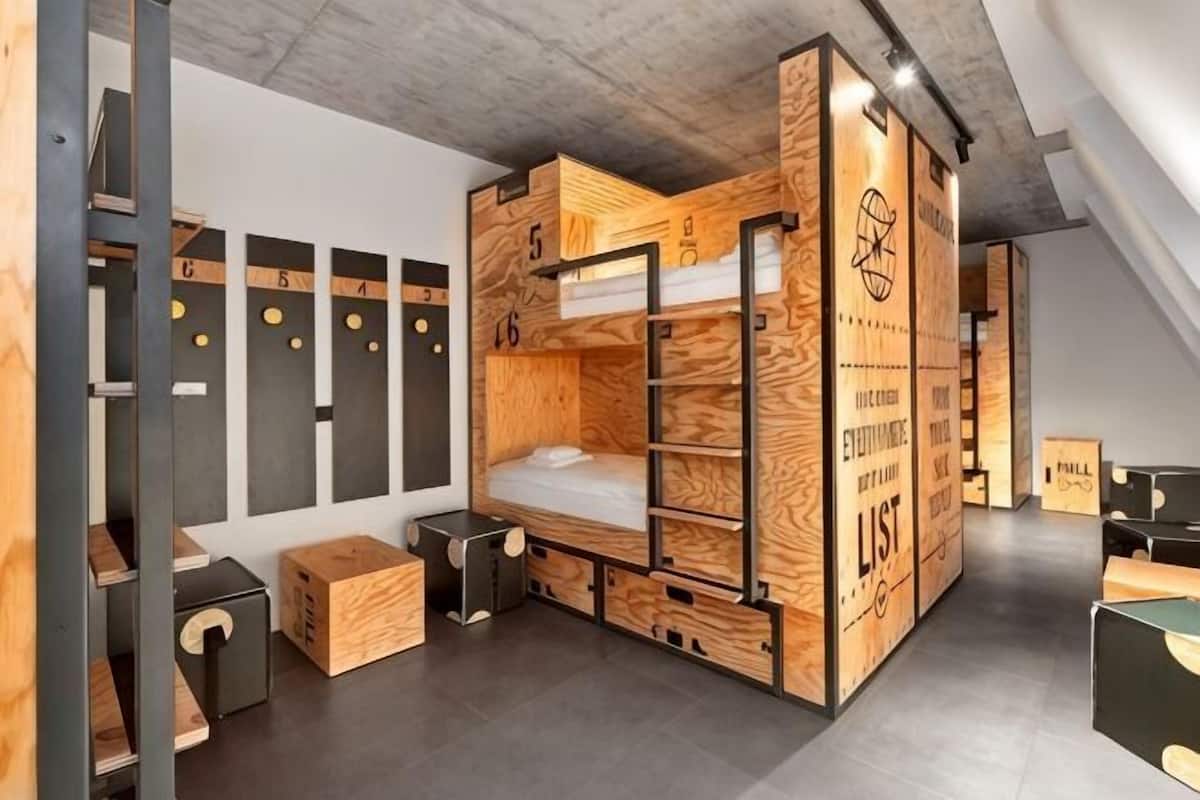 A bunk bed room with a wooden design, a desk, and a chair.