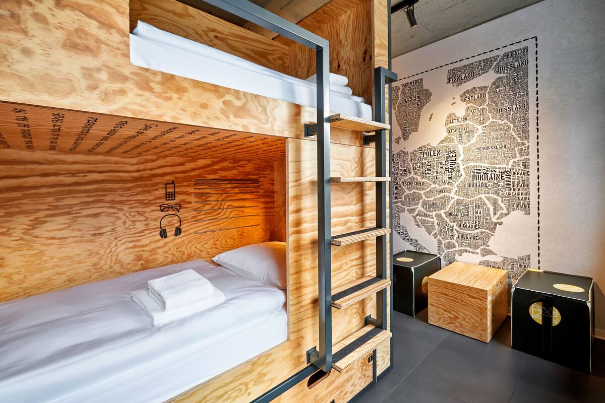 A bunk bed with a wooden headboard, a small shelf, and a map on the wall.