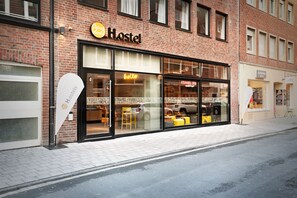A Hostel with a 'hello' sign, large windows, and a visible 'Blickwinkel' store across the street. - Stories by Grimm‘s (Münster)