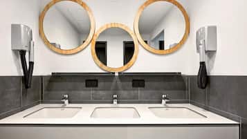 A modern bathroom with three sinks, two towel dispensers, and three wall-mounted mirrors.