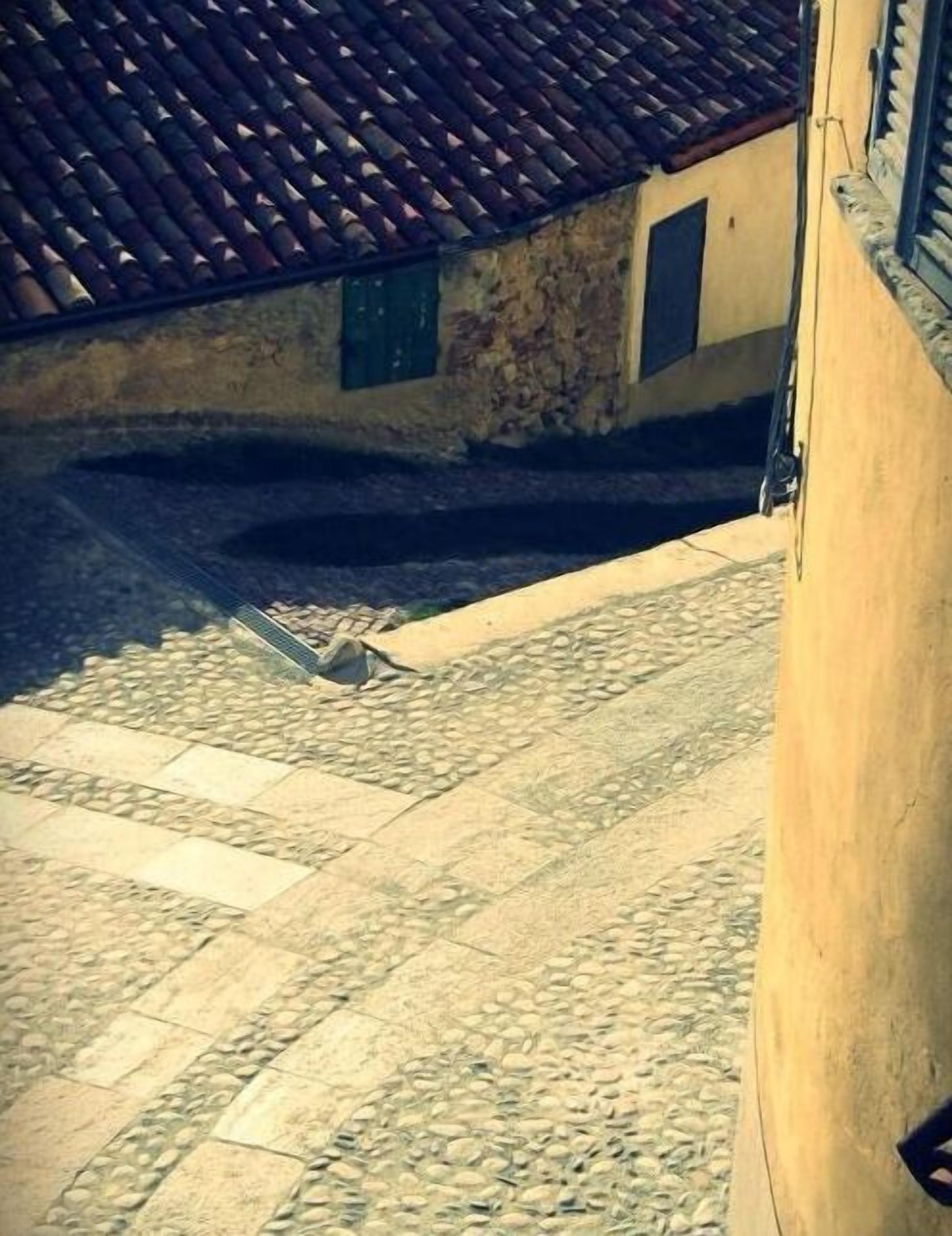 Un patio empedrado con tejado de baldosas y pared de piedra.